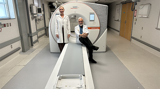 Eric Hoffman and Jessica Sieren in front of a PCD-CT scanner.