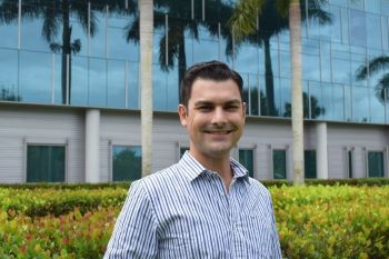 Man smiling in front of building.