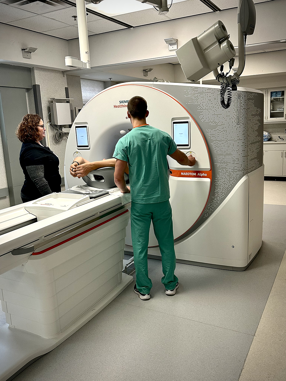 Jarron Atha and Kelly Stark position a study participant in a PCD-CT scanner.