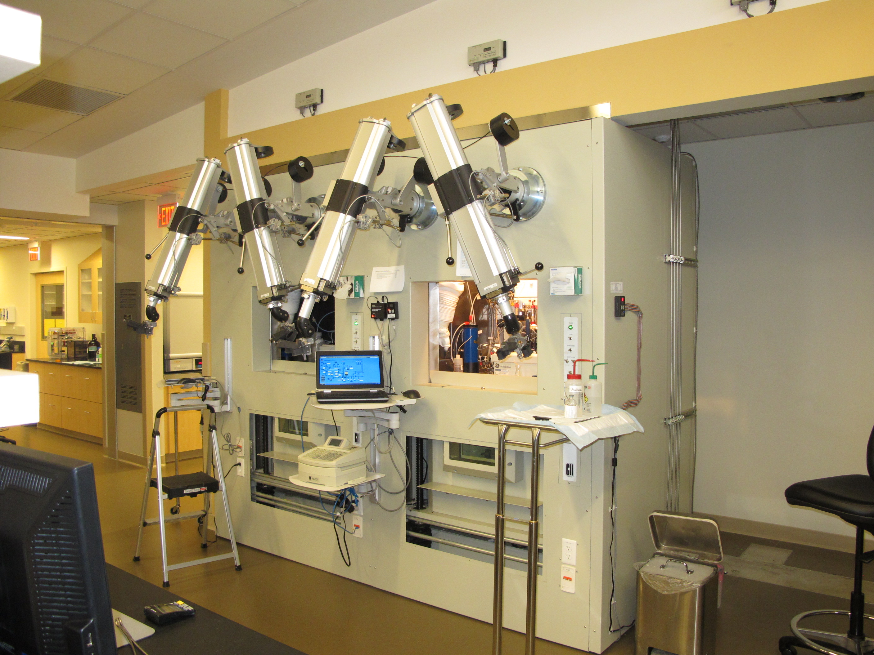 Photograph of two "hot cells" in a laboratory. Hot cells are a device with external controls that manipulate robotic arms inside a closed container. Hot cells permit laboratory personnel to safely handle highly radioactive material. 
